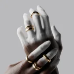 Artistic white painted hands modeling gold jewelry rings