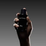 Hand modeling Dior Sauvage men’s fragrance against a dark background