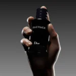 Hand modeling shot featuring Dior Sauvage fragrance on dark background