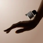 Minimalist hand modeling holding perfume bottle on extended hand