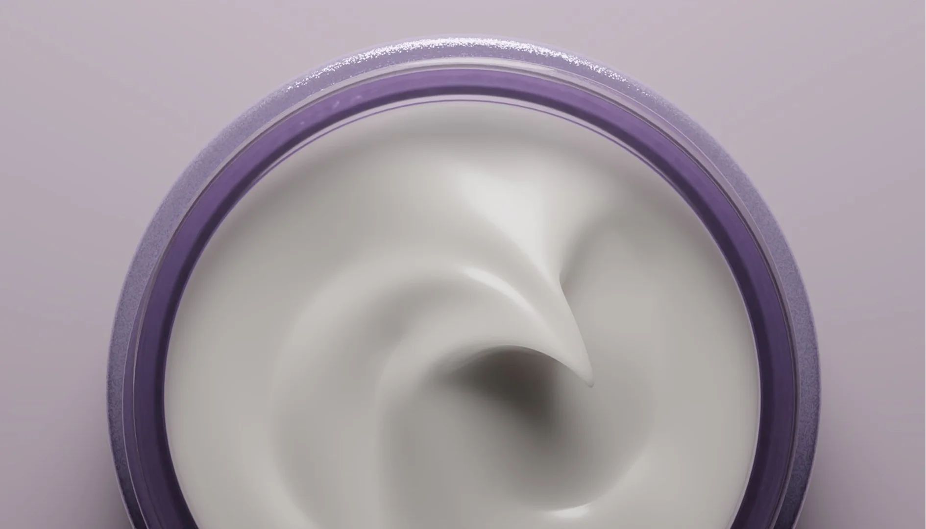 A detailed close-up view focusing on the smooth, glossy peak of white face moisturizer inside a purple cosmetic container container.